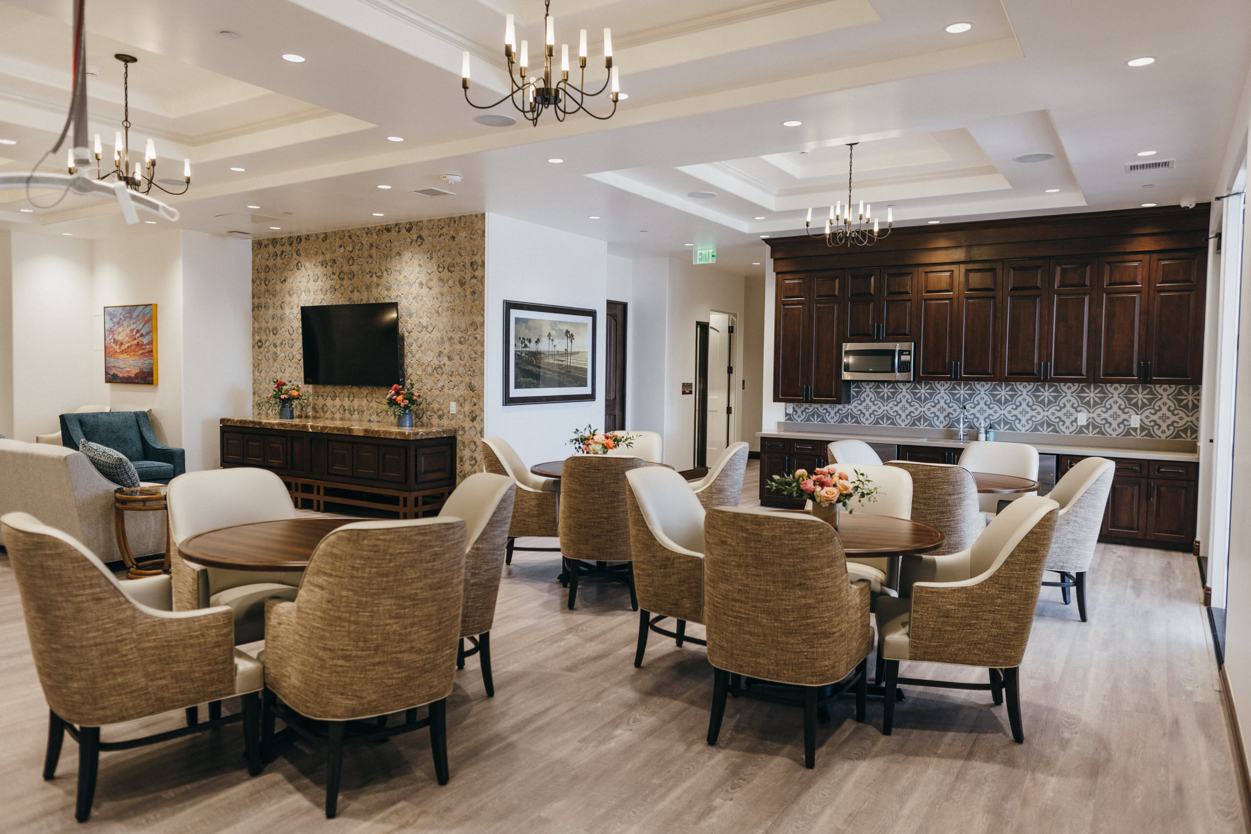 Seniors can relax in a comfortable assisted living community at Raya's Paradise in Orange County in a lounge with friendly caregivers, showcasing amenities like open seating areas, dining spaces, and lush outdoor courtyards.