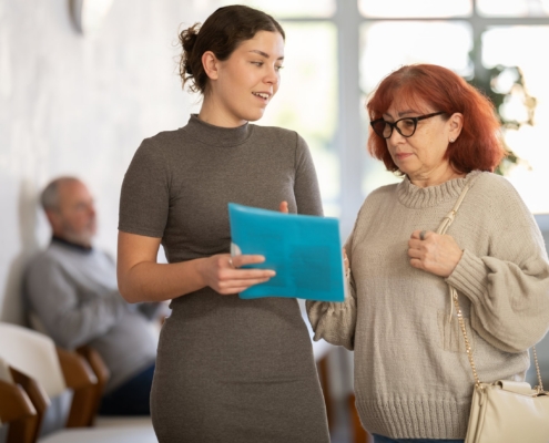 A younger woman reviews documents with an older woman, illustrating discussions about assisted living care concerns and resident rights.
