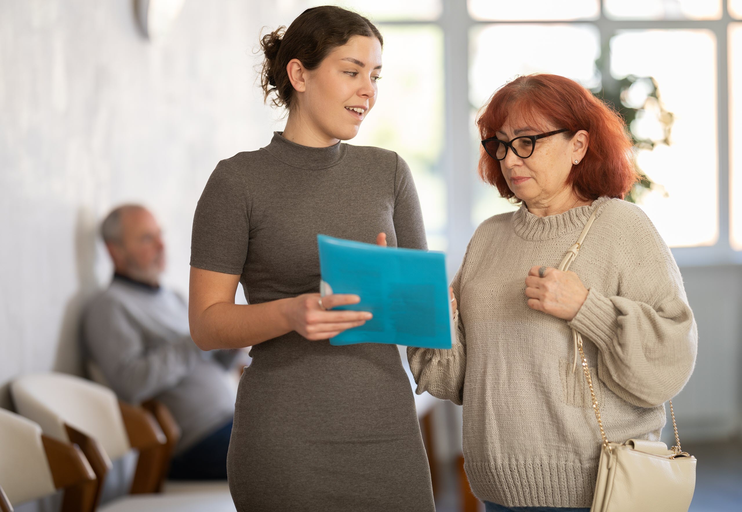 A younger woman reviews documents with an older woman, illustrating discussions about assisted living care concerns and resident rights.