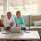 Older couple reviews documents and a laptop at home while exploring assisted living options and senior care transitions in California.