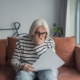 Older woman looks worried while reviewing paperwork at home, reflecting concerns about assisted living costs and financial uncertainty.